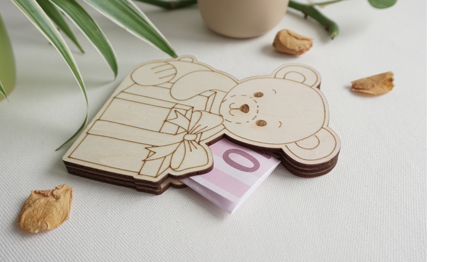 Sitzendes Bärchen mit Geschenk vor sich, aus hellem Holz. Seitlicher Schlitz, zum einstecken von gefalteten Geldscheinen oder Standard Geschenkkarten. dekorative Geschenkidee. Flach, aus drei lagen Holz. kann stehen oder liegen.