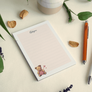 Liniertes Notizpapier mit Punkt-Raster, apricotfarbener Hintergrund und Illustration eines sitzenden Teddybären im pinken Kleid