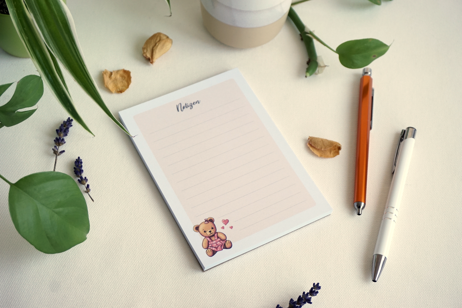 Liniertes Notizpapier mit Punkt-Raster, apricotfarbener Hintergrund und Illustration eines sitzenden Teddybären im pinken Kleid