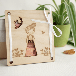 nahezu Quadratisches Geldgeschenk aus Buchenholz für Mädchen zur Kommunion mit Ausschnitten für Geldscheine in Form eines Kleides und einer Taube, verziert mit Blumen-Gravuren.